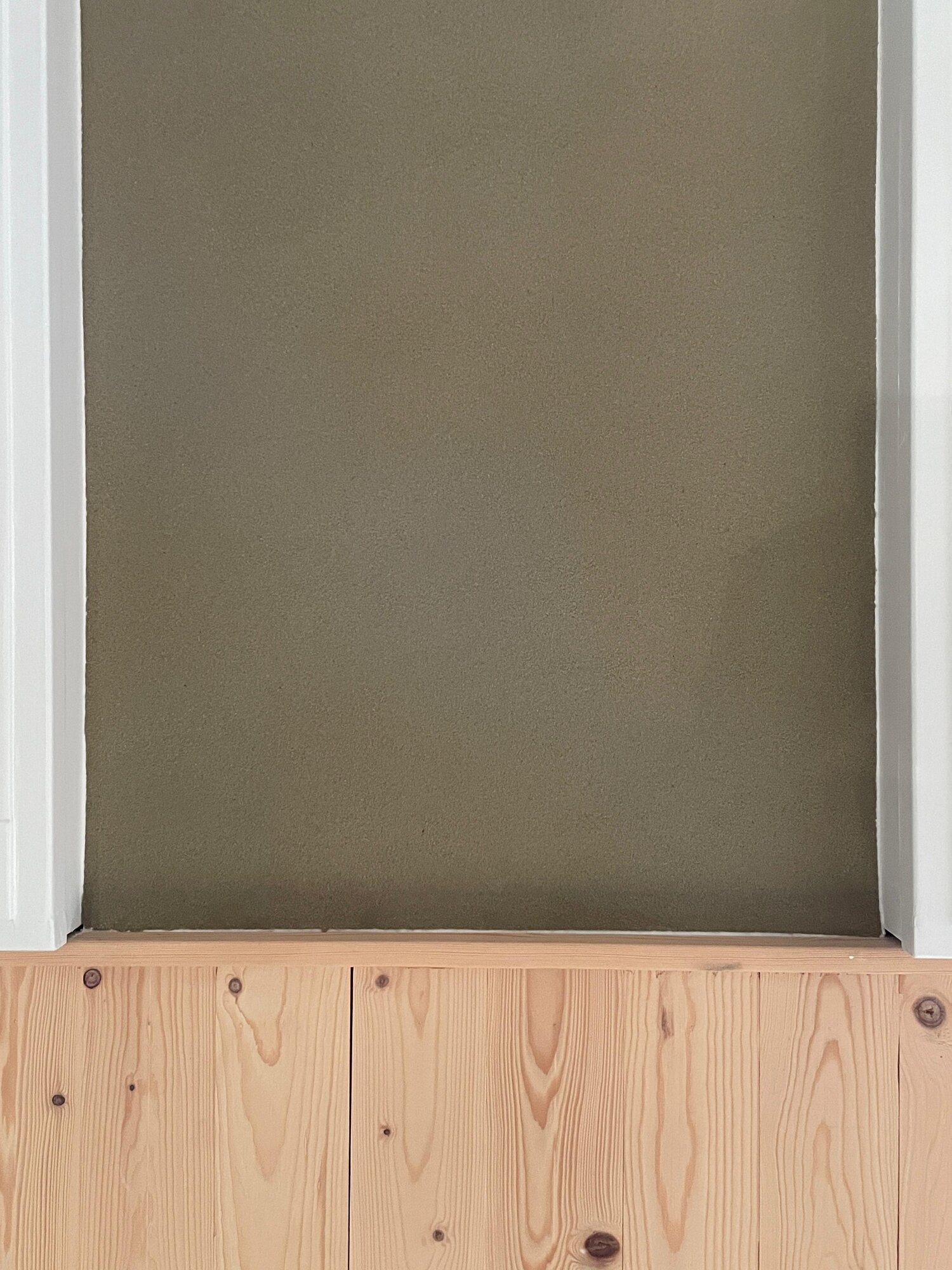 Close-up of an olive green BioStuc wall finish above pine wood panelling