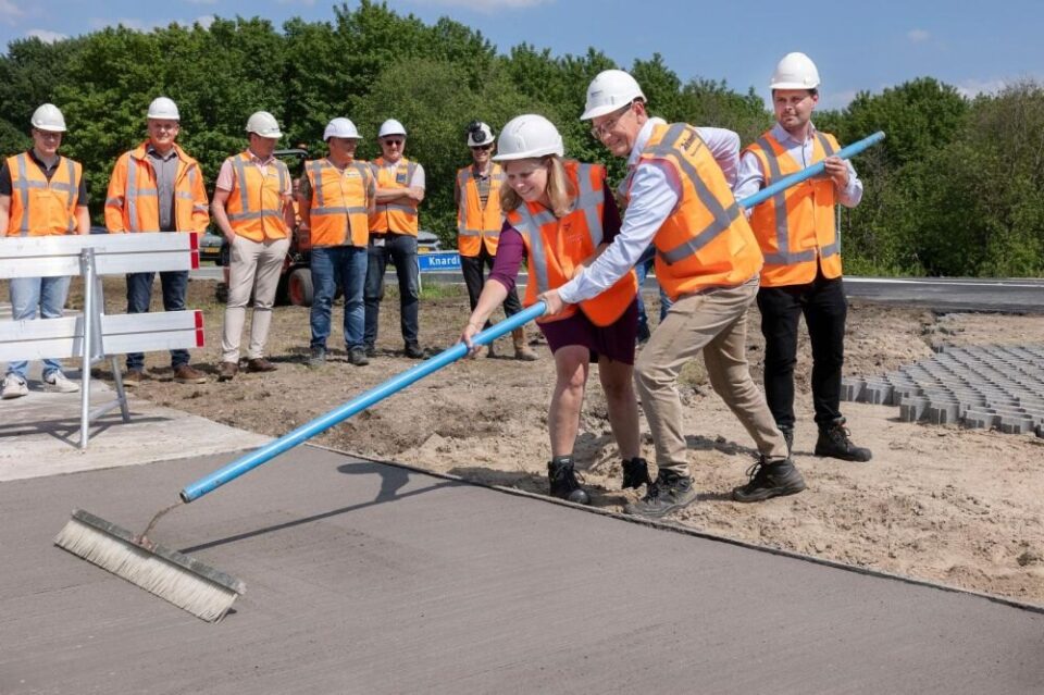 People in hard hats smoothing fresh concrete with a long-handled float