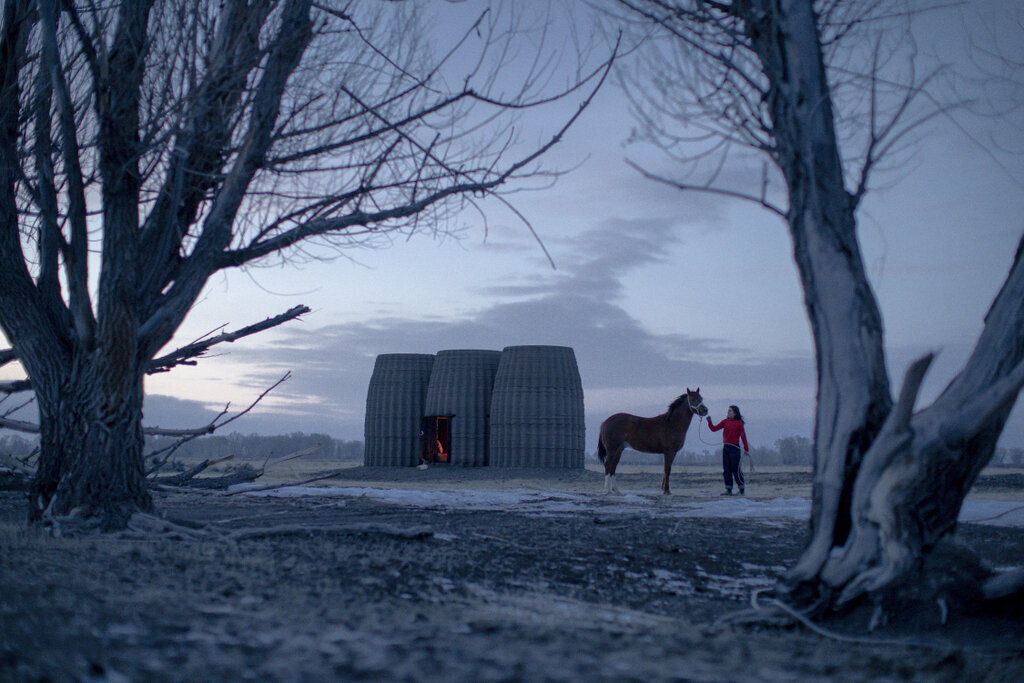 Three 3D printed adobe volumes of Casa Covida in a desert landscape at dusk