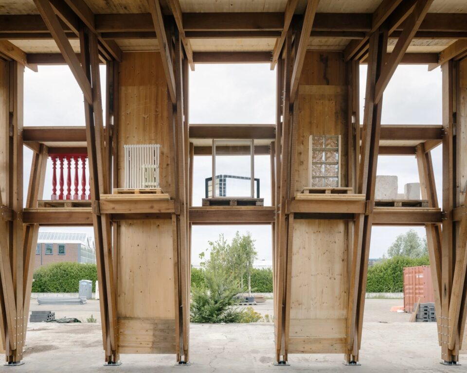Front view of a reclaimed timber frame with vertical panels and material samples on shelves